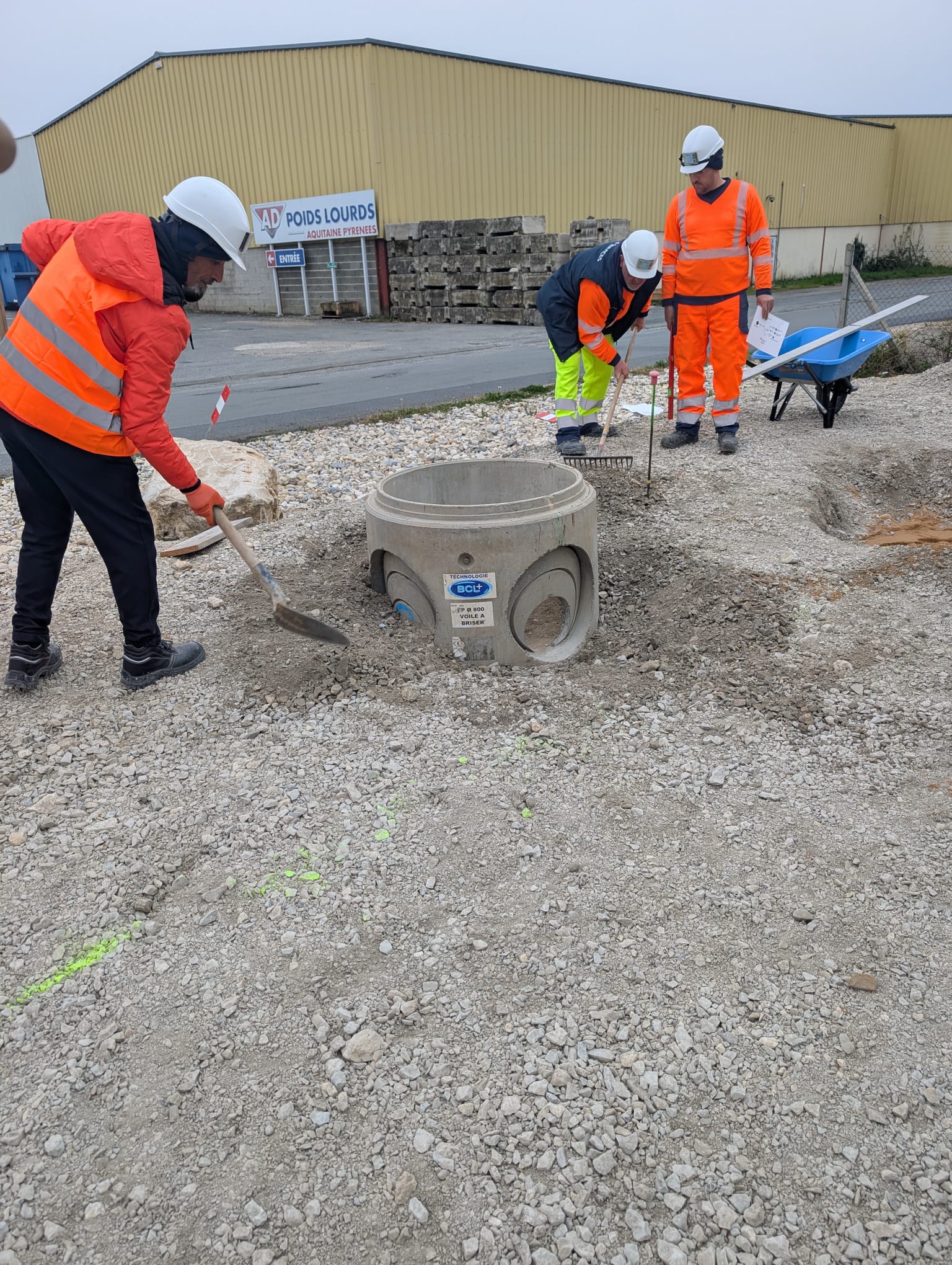 3 stagiaires en EPI complet travaillant autour d'un regard préfabriqué